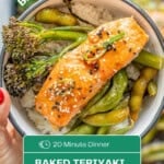 A bowl with green vegetables and a glazed piece of salmon sprinkled with sesame seeds being held above a tray of salmon and vegetables. With text overlay for Pinterest.