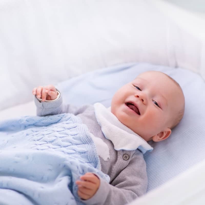 baby happy in bed with blue blanket