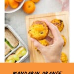 Hand holding a Mandarin muffin with rest on bench . text overly: Mandarin Orange Muffins.