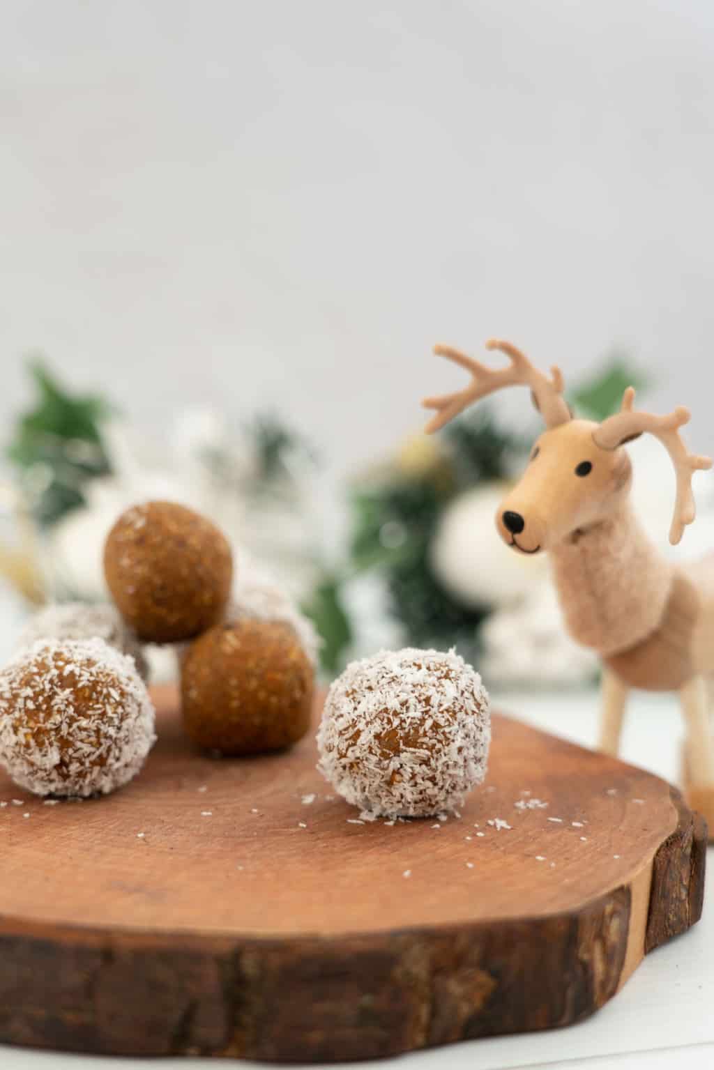 A reindeer toy looking at carrot bliss balls on a wooden block