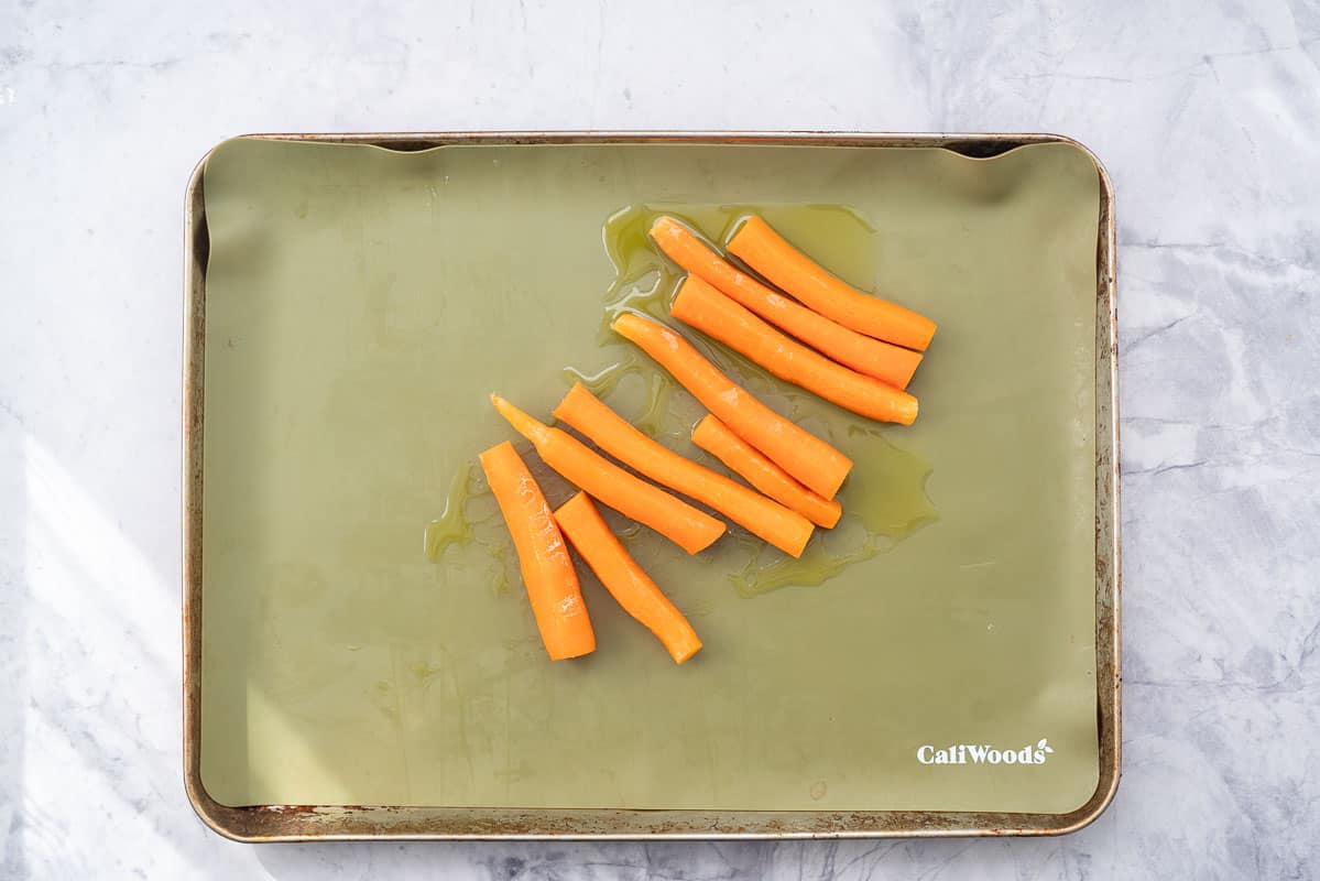 Peeled and oiled carrots on a lined baking tray