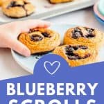 child's hand reaching for a blueberry scroll