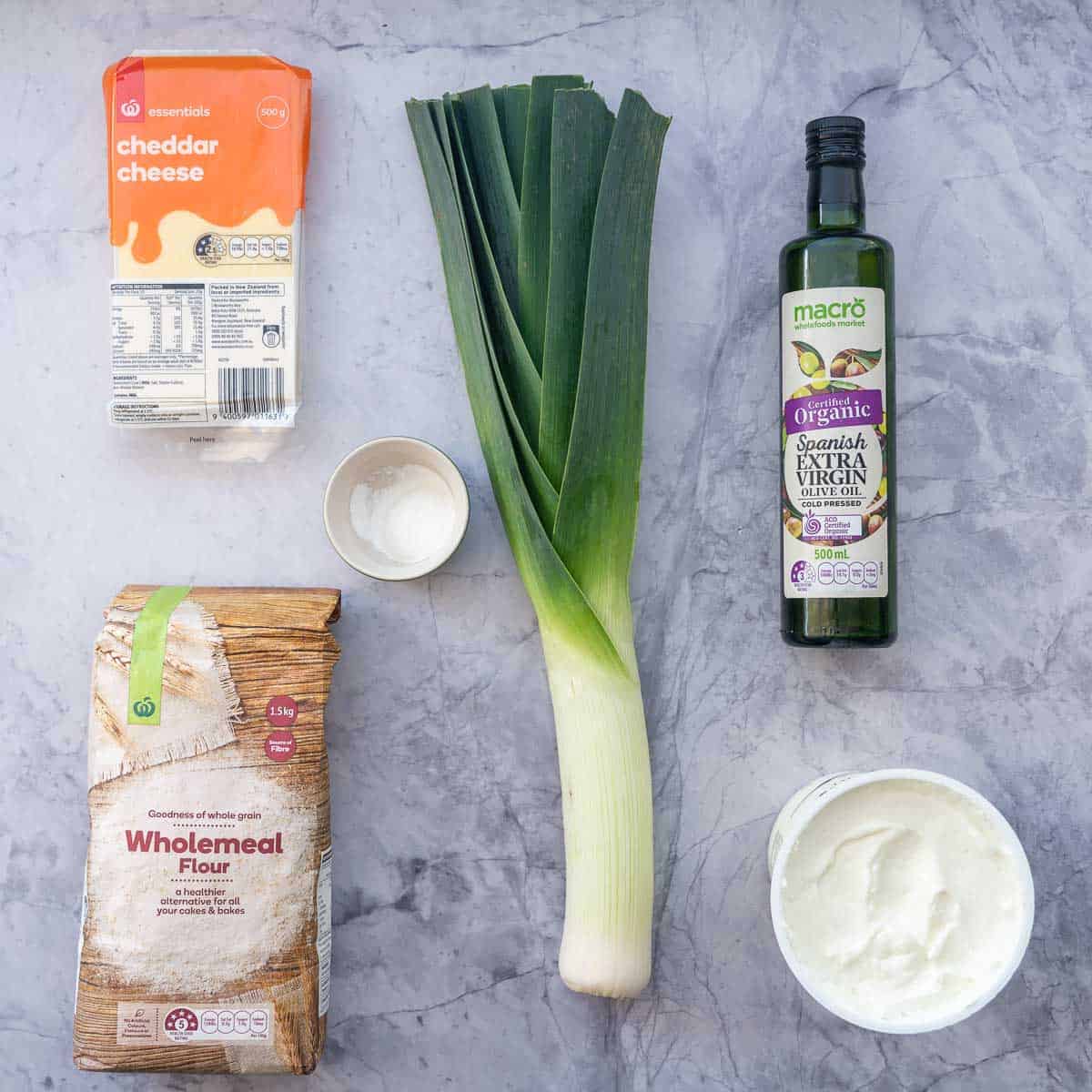 The ingredients to make yogurt dough scrolls with cheese and leek filling laid out on a bench top