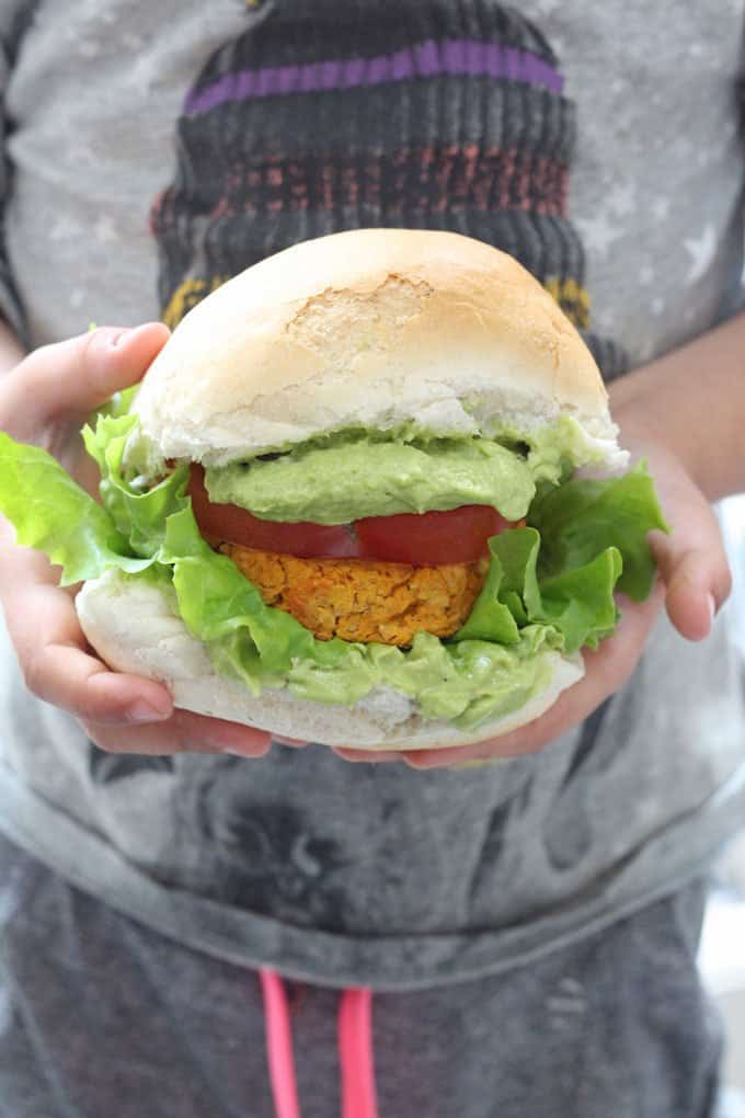 Sweet potato chickpea veggie burger being held by two hands.