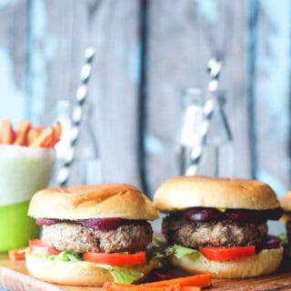 Two vegetable packed burgers sitting on chopping board.