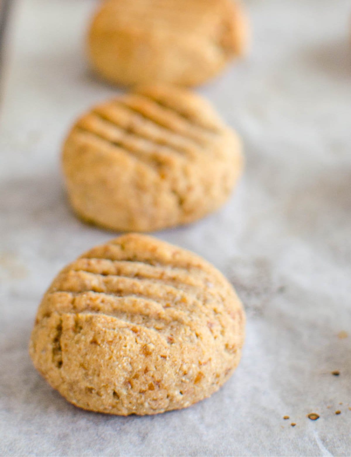 Small golden cookies with fork marks on a lined baking sheet.