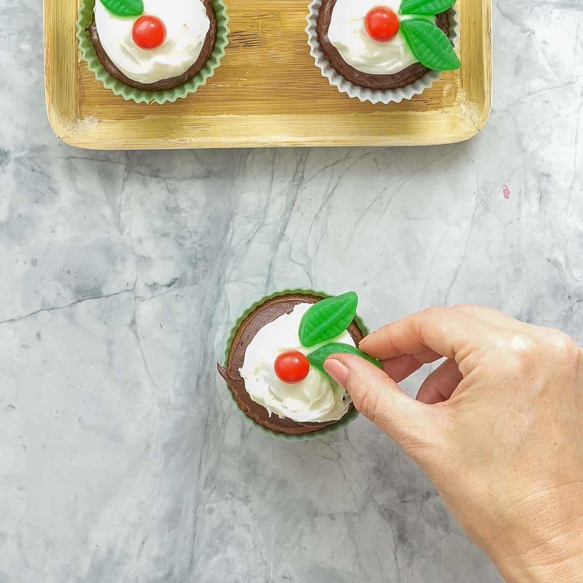 Decorate the frosted cupcake with 1 Jaffa (or red ball-shaped sweet) and 1-2 spearmint leaves to look like a sprig of holly