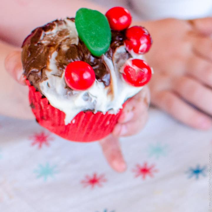 A cupcake messily decorated with candy and frosting by a child to look a little like a figgy pudding. 