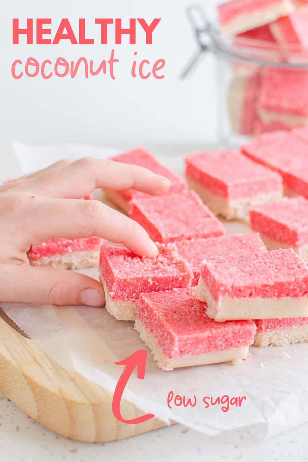 childs hand reaching for a slice of pink and white coconut ice