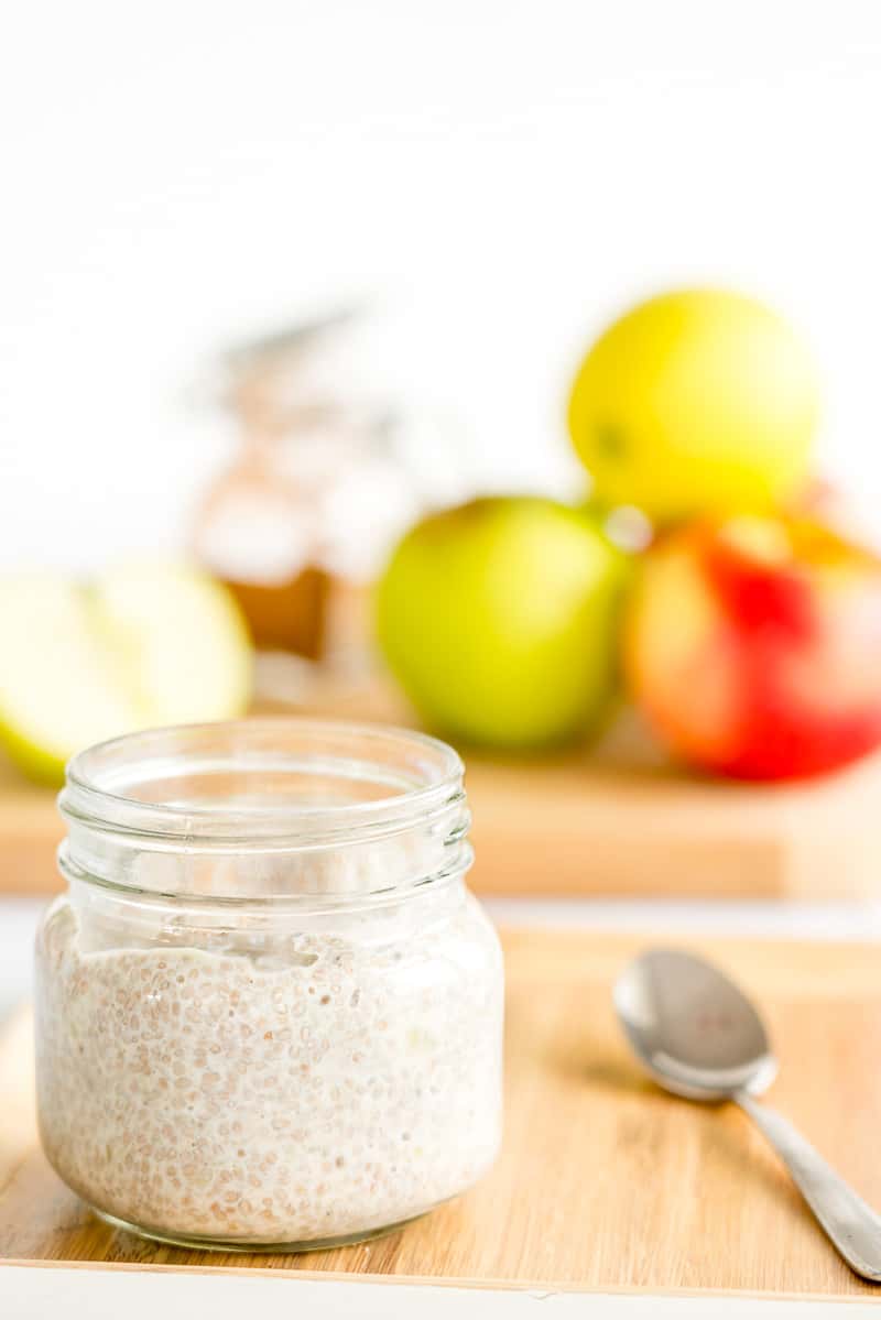 jar of apple pudding with a spoon next to it, apples in the background