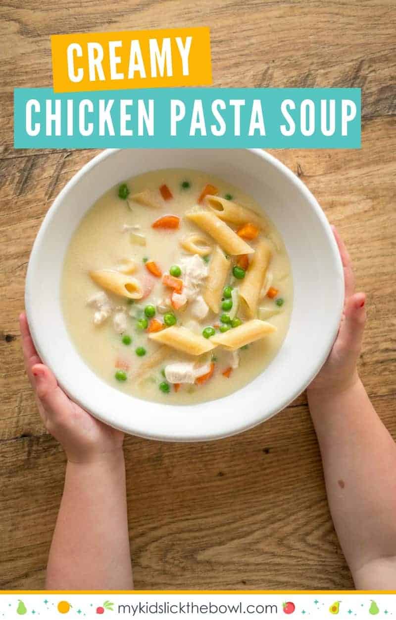 creamy chicken pasta soup in a white bowl on a wooden surface, childs hands reaching out to grab it