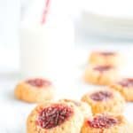 Peanut butter and Jam Thumbprint Cookies on a white table with a bottle of milk and white side plates