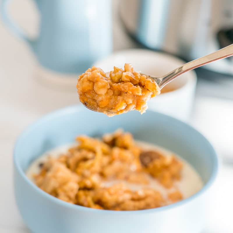 slow cooker porridge, spoonful up close above a bowl of oatmeal