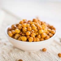 Crunchy garlic roasted chickpeas, in a small white bowl on a linen surface