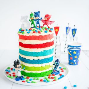 colourful layered birthday cake filled with butter cream, topped with pj masks characters