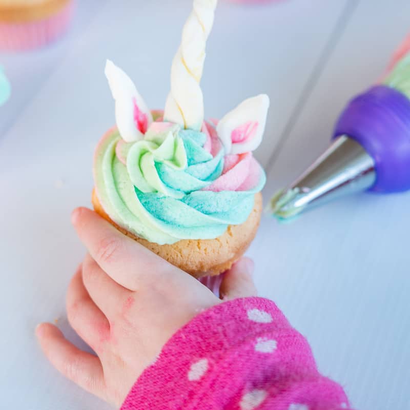 Unicorn cupcakes- child hand reaching for a cupcake