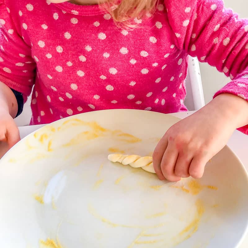 Child rolling an edible unicorn horn made out of fondant