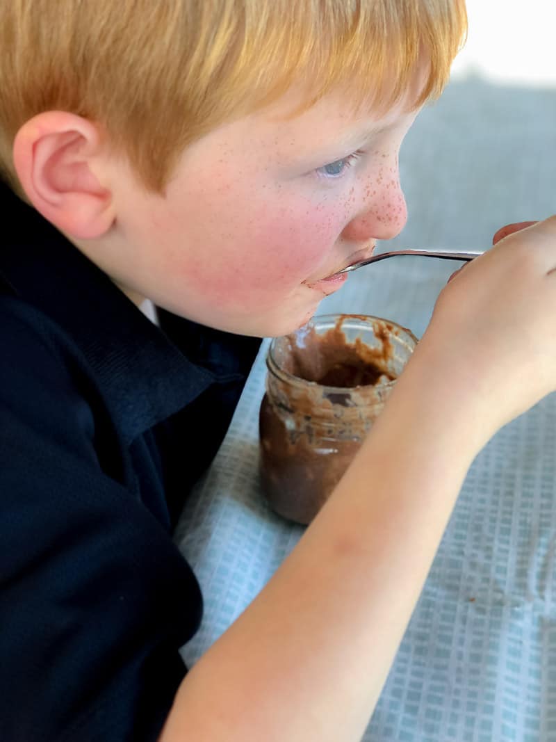 Young boy eating a chocolate chia pudding with a spoon