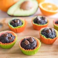 Avocado muffins on a wooden chopping board oranges and avocado in background