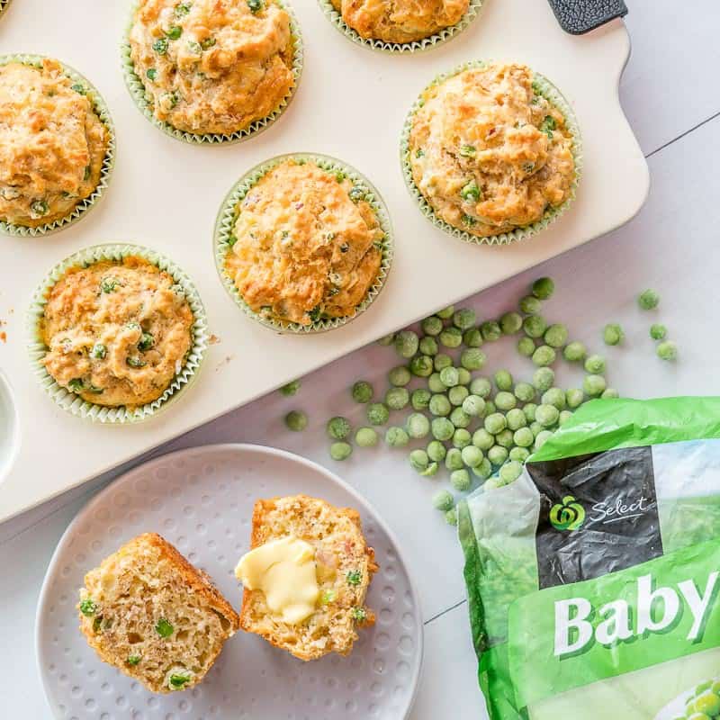 Savoury muffin batter uncooked in a cream muffin tin with a bag of frozen peas