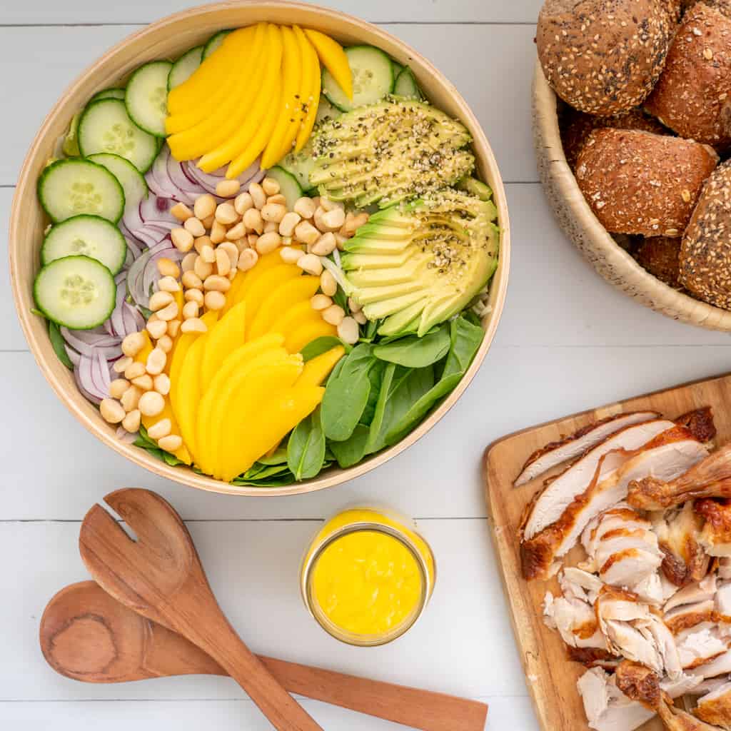 Salad served with sliced roast chicken and bread rolls