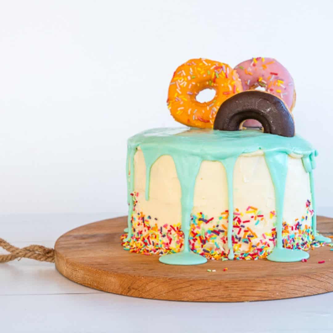 colourful doughnut birthday cake with blue drip icing and sprinkles around the base