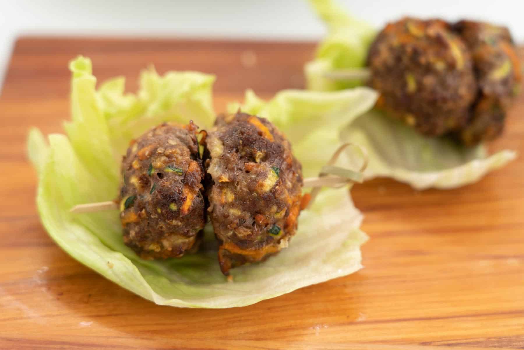 2 plain rissoles on a small bamboo skewer sitting on a lettuce leaf