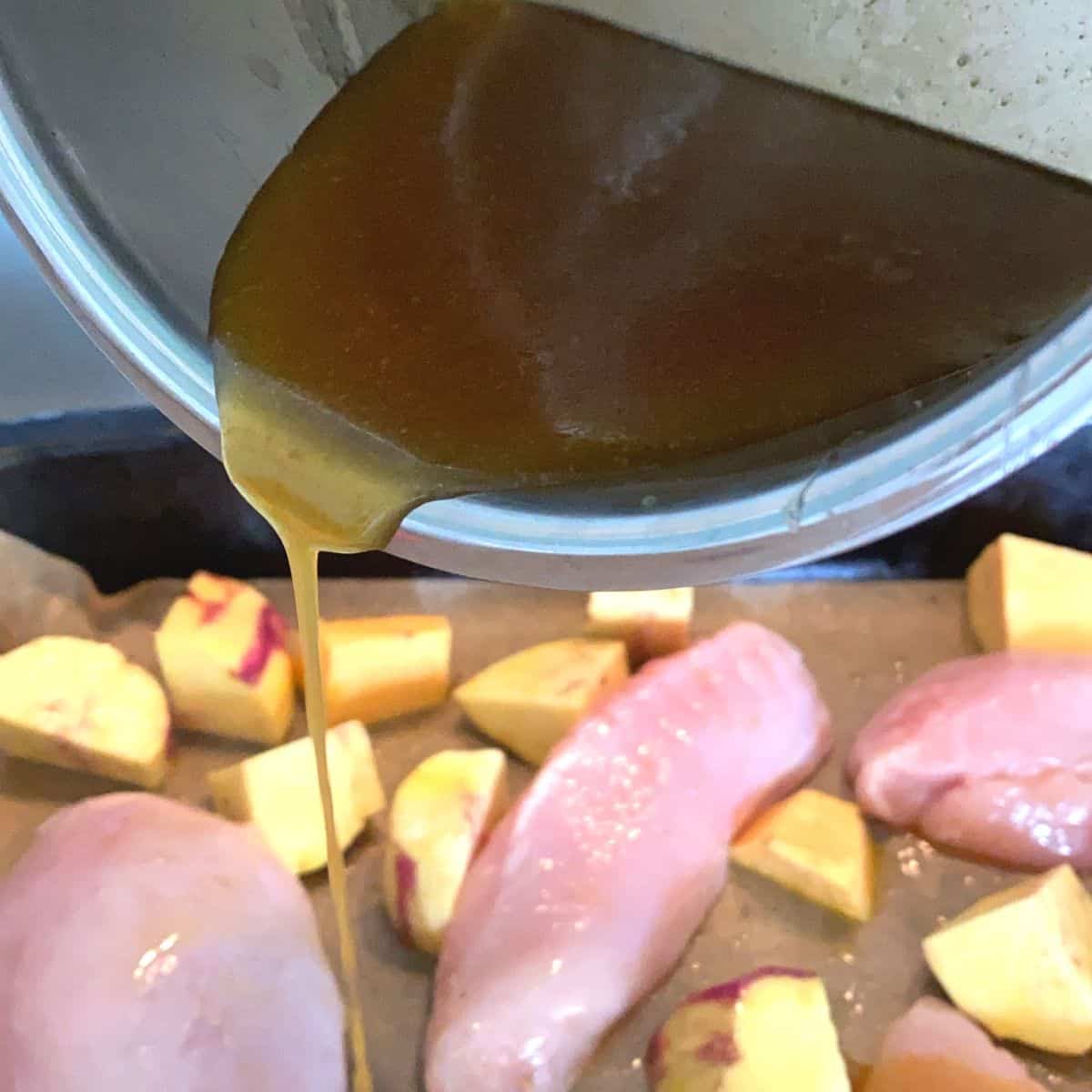 Pouring a saucepan of maple syrup caramel over chicken breasts and sweet potato