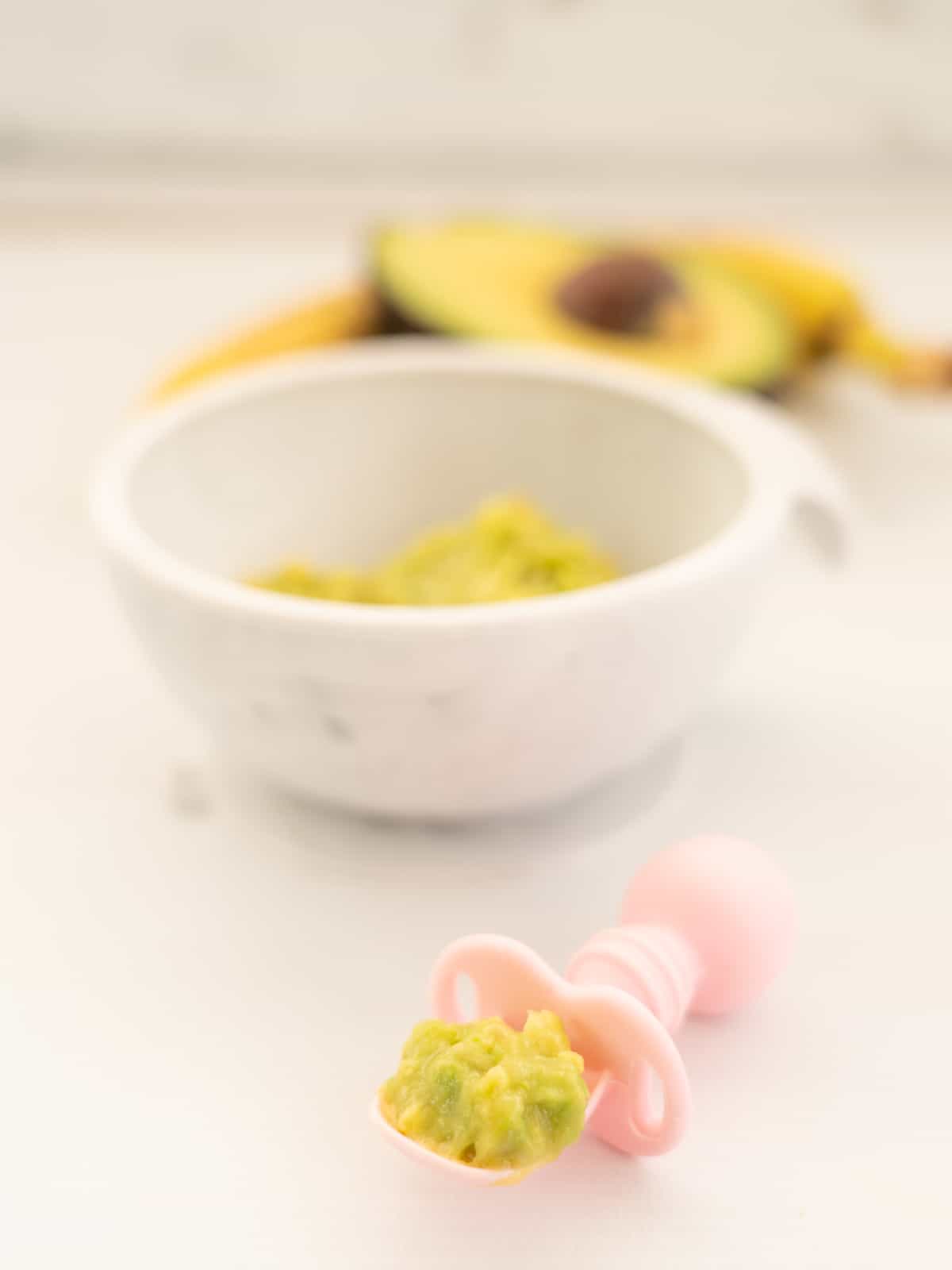 avocado baby food pre-loaded on a pink silicone baby spoon