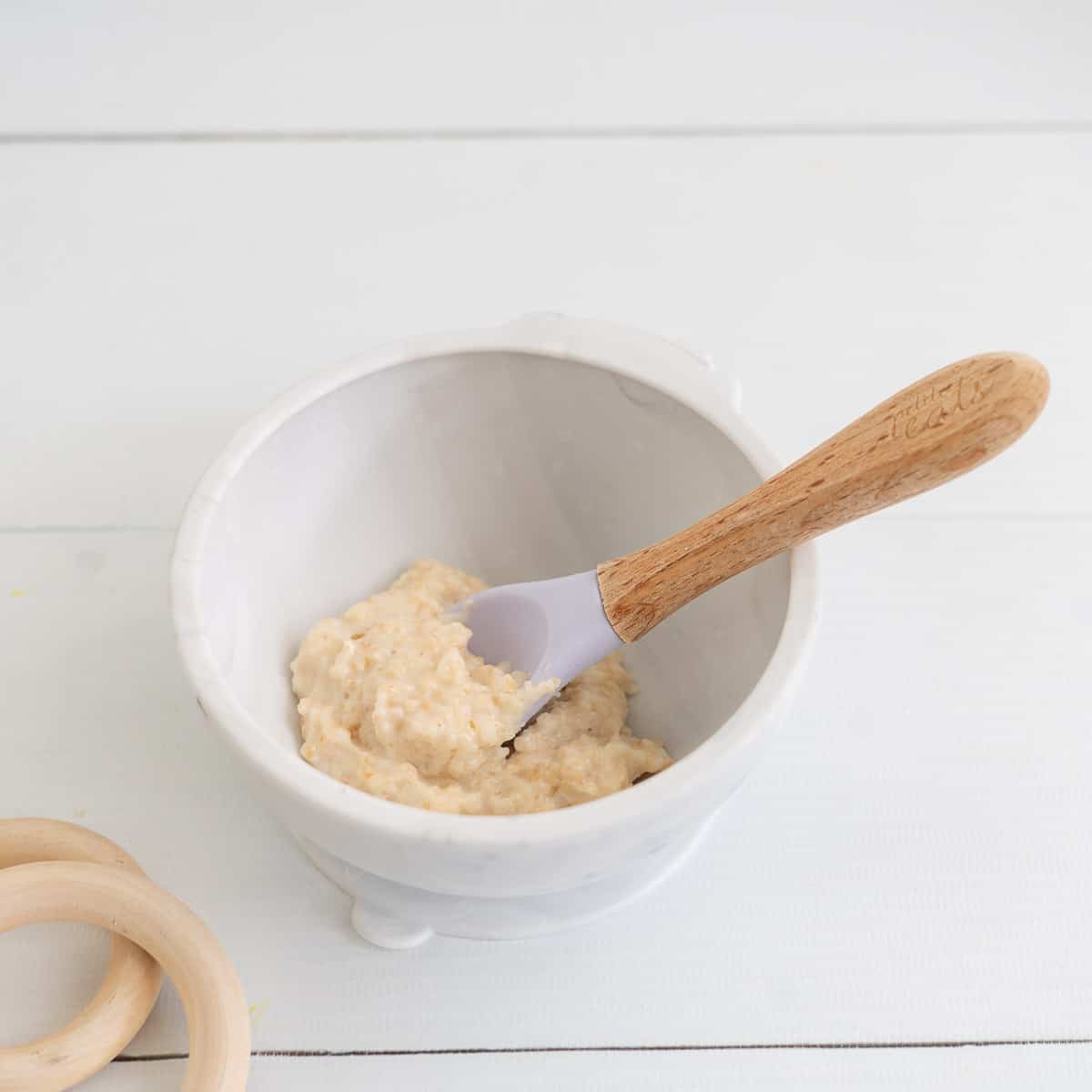 Baby porridge in a light grey baby bowl with bamboo handled baby spoon