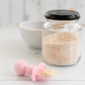 spoonful of cooked baby porridge on a pink baby spoon