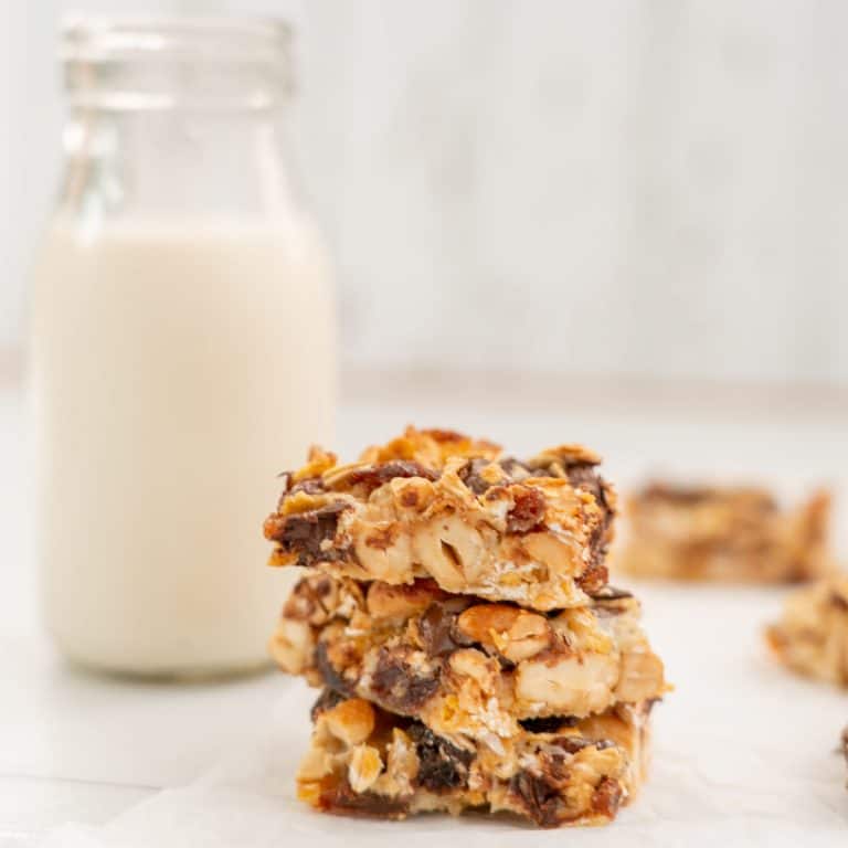 3 pieces of condensed milk slice stacked in a tower, sitting next to a small glass bottle of milk