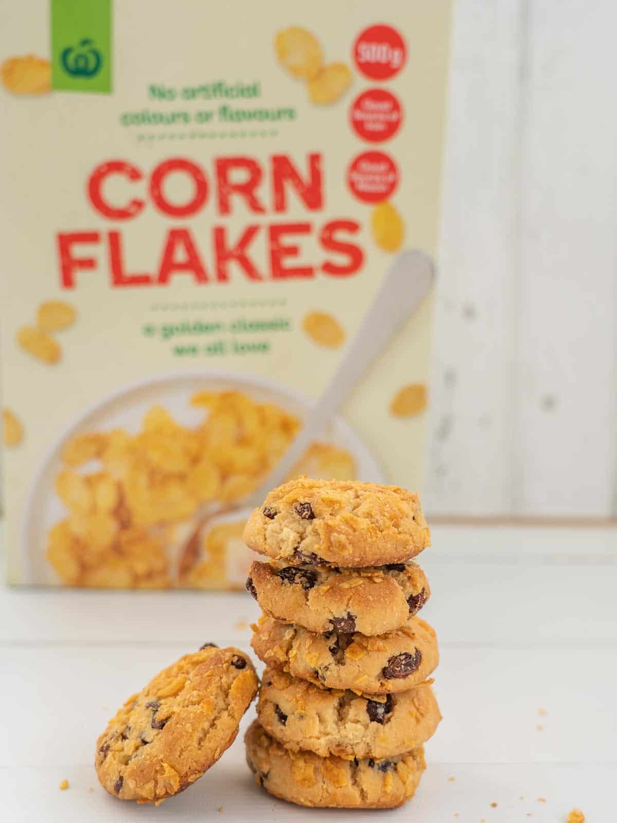 Stack of cookies sitting in front of a box of cornflakes