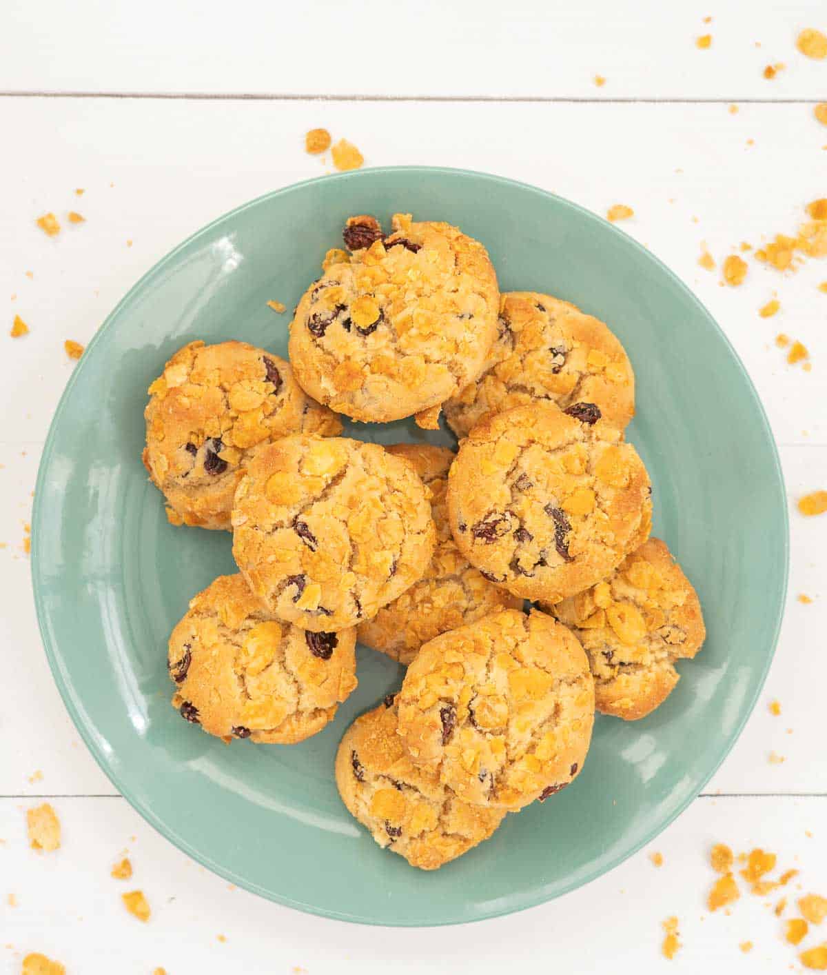 Cookies on a turquoise plate, cornflakes on the table top around the plate 