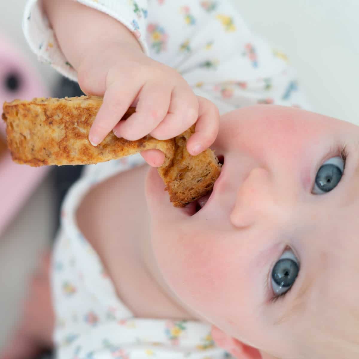 a blued eyed baby eating eggy bread