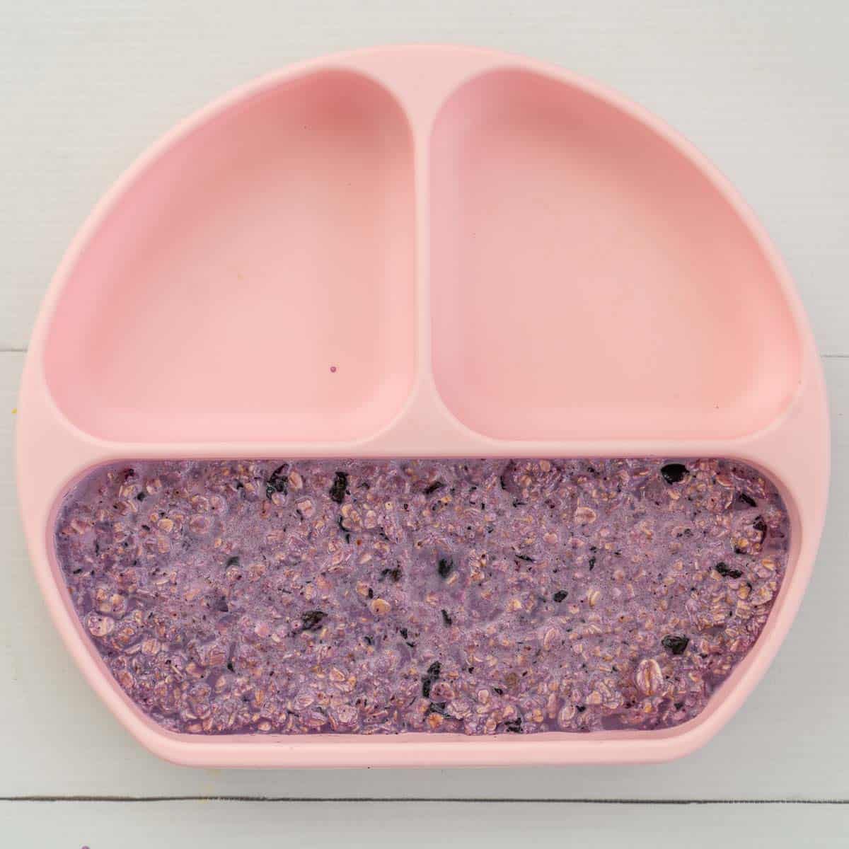 oatmeal coloured purple by blueberries in a divided baby plate