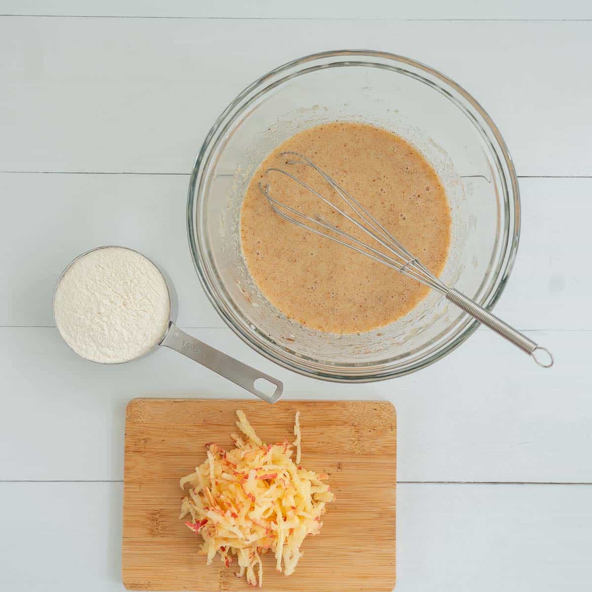 wet ingredients whisked, self-raising flour and grated apple ready to be added