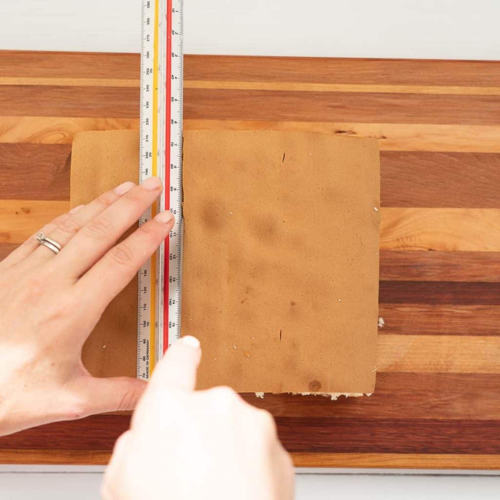 female hands cutting sponge cake using a ruler as a guide