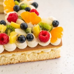 close up of fruit decorations on a birthday cake, raspberries, blueberries, kiwifruit, clementines