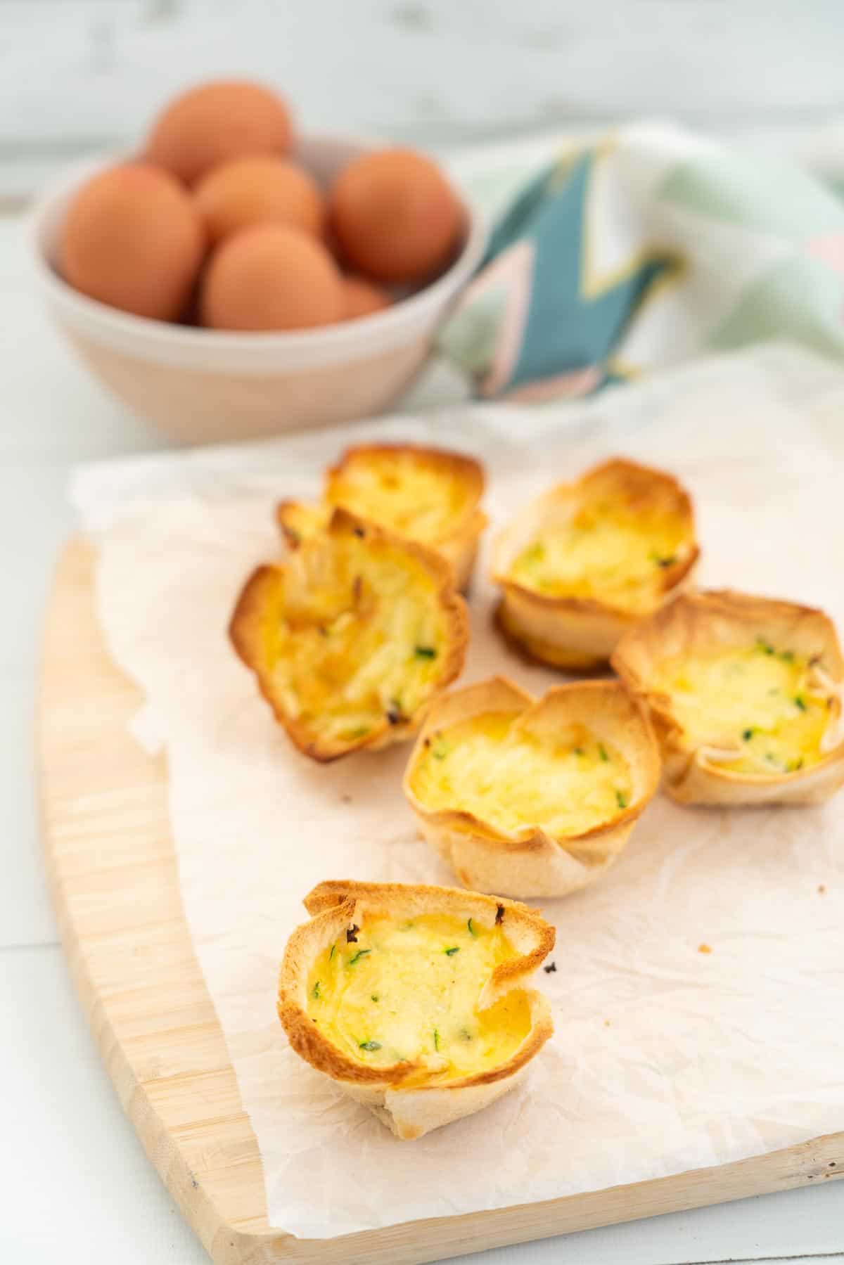 6 mini quiches with bread case bases sitting on a wooden chopping board