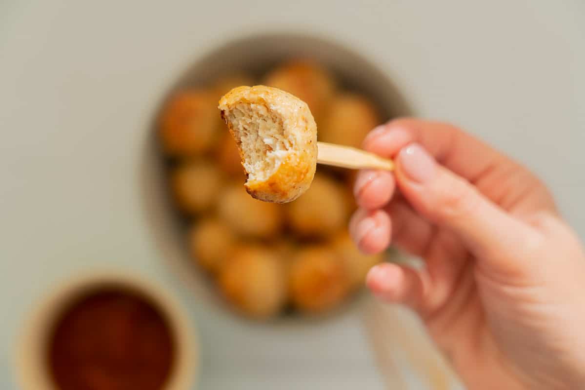 A chicken rissole that has had a bite taken out of it, so that the inside is visible, you cannot see any of the green from the broccoli