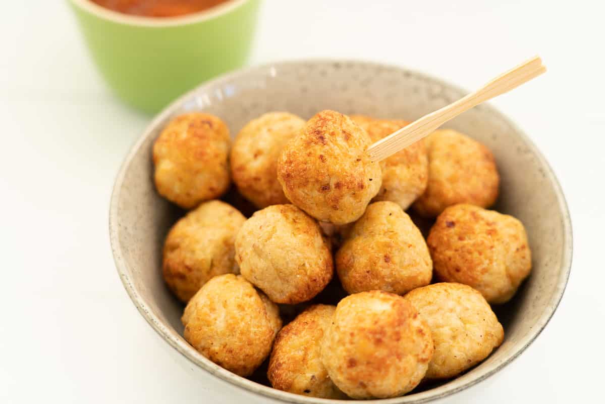 a bowl full of chicken meatballs with a bowl of tomato relish for dipping