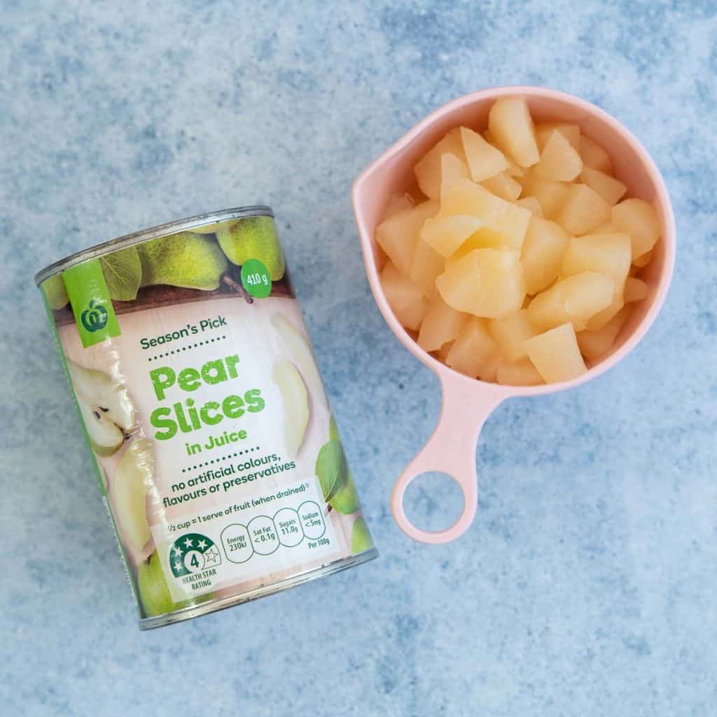 A tin of pears next to a measuring cup filled with diced tinned pears