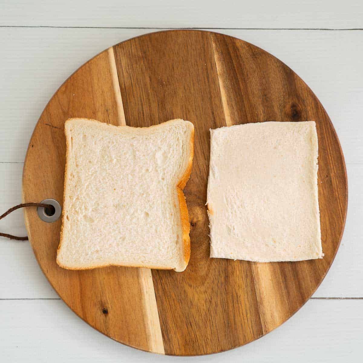 two slices of bread on a wooden chooping board, one with the slices removed