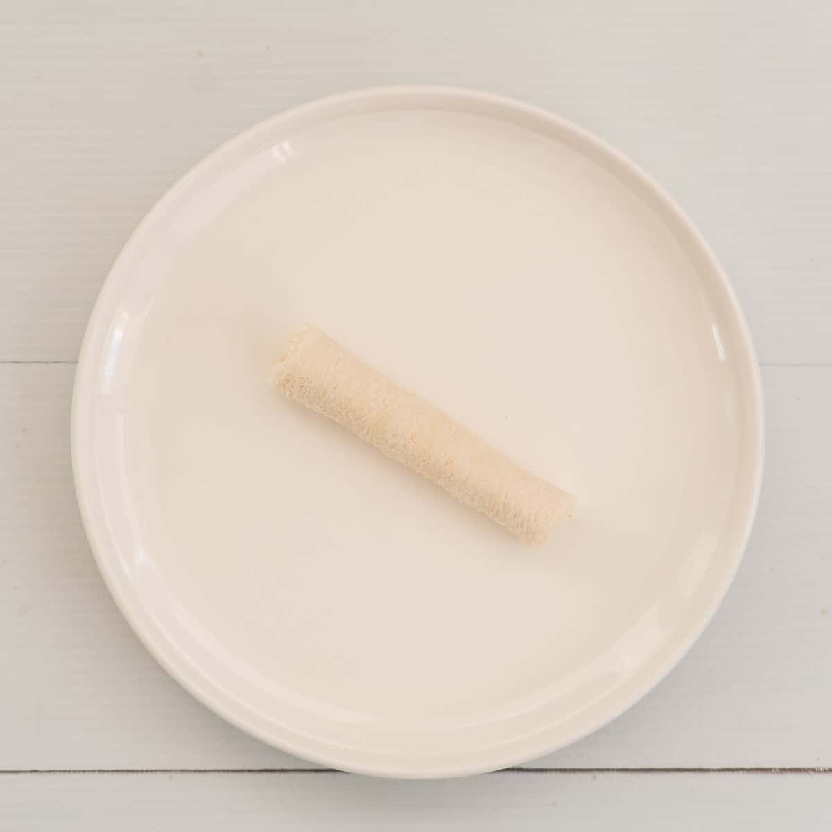 Roled slice of bread on a white plate