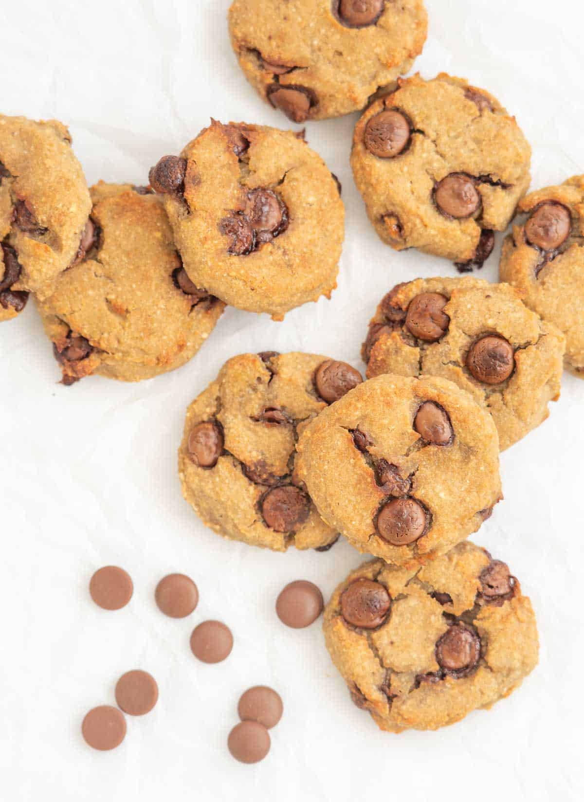 10 chickpea cookies lying haphazardly on baking paper with chocolate chips