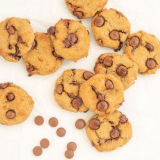 10 chickpea cookies lying haphazardly on baking paper with chocolate chips
