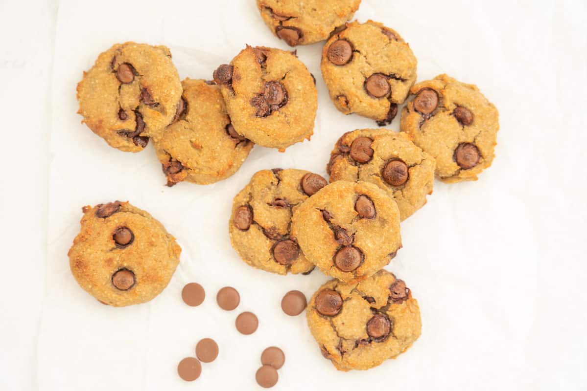 10 chickpea cookies lying haphazardly on baking paper with chocolate chips