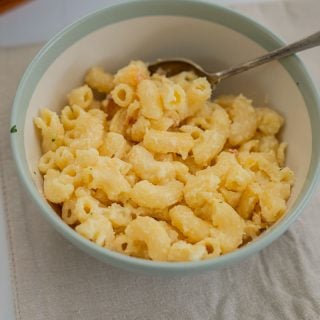 a bowl of mac and cheese sitting on a placemat with a spoon