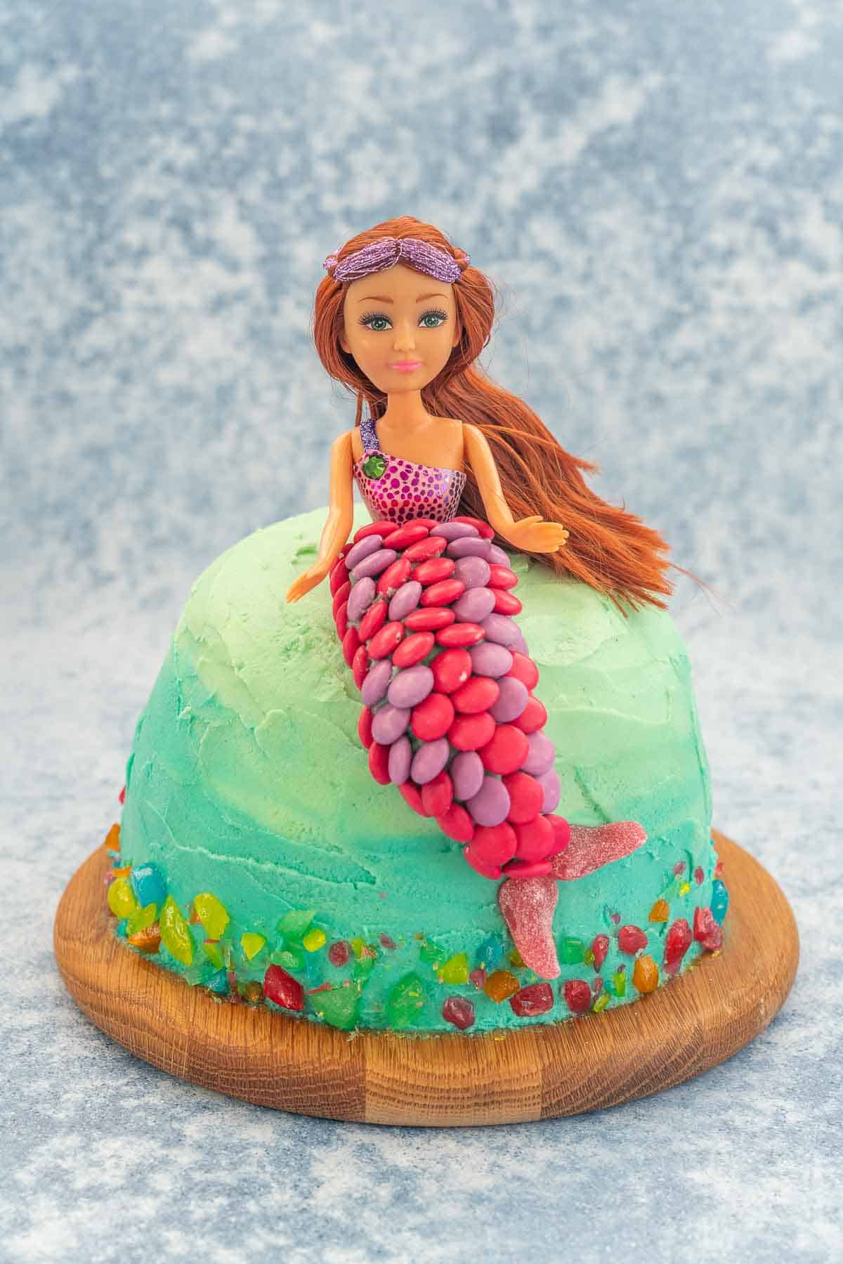 Ombre ocean coloured cake with a mermaid cake topper decorated with colourful sweets